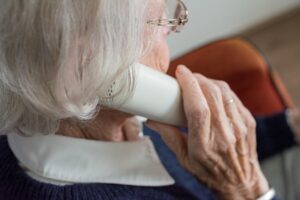 Senior woman listening to her church service on the phone at home